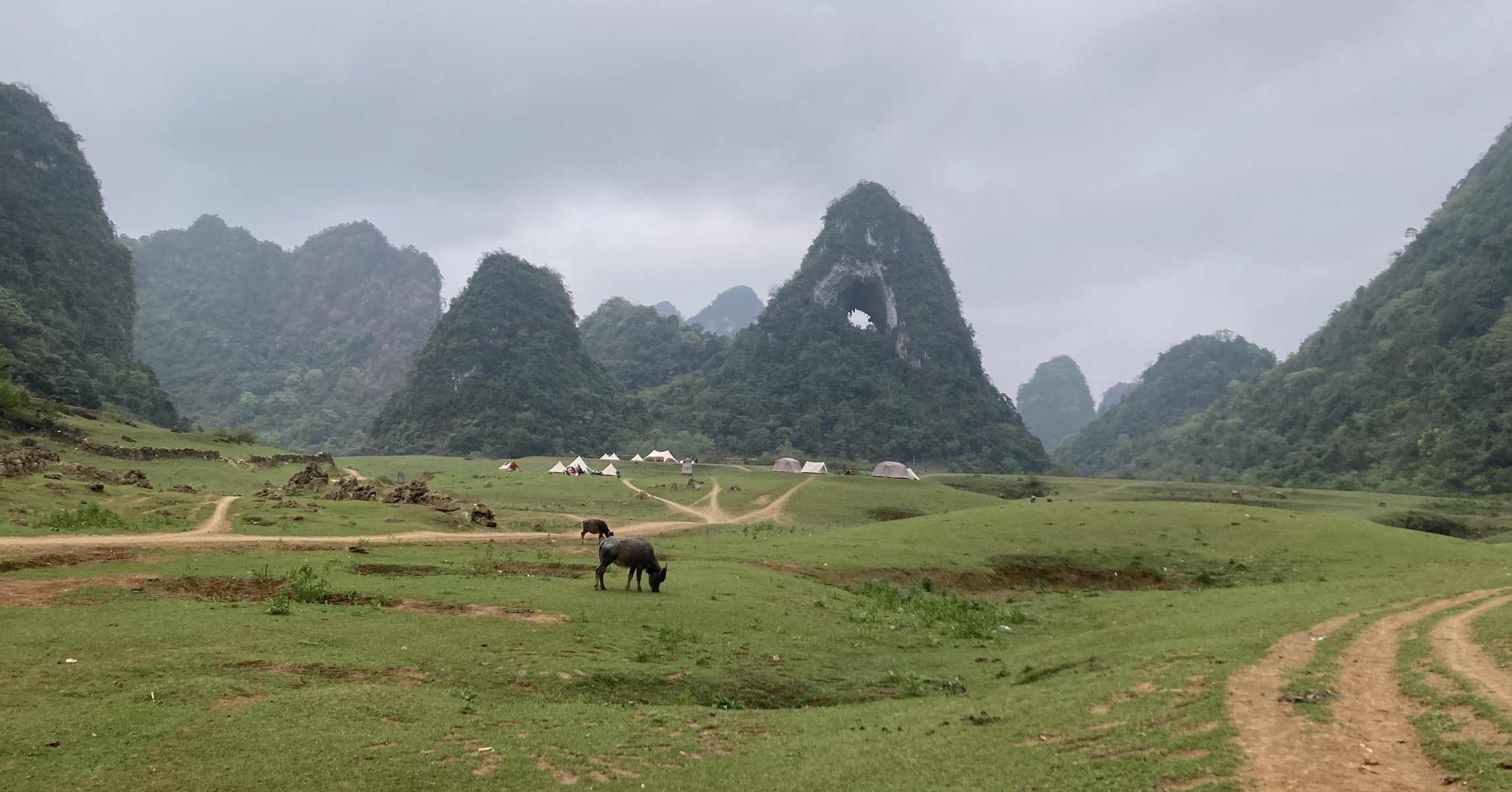 Núi Mắt Thần (Núi Thủng) với lỗ thủng giữa thảo nguyên xanh và lều cắm trại ở Cao Bằng