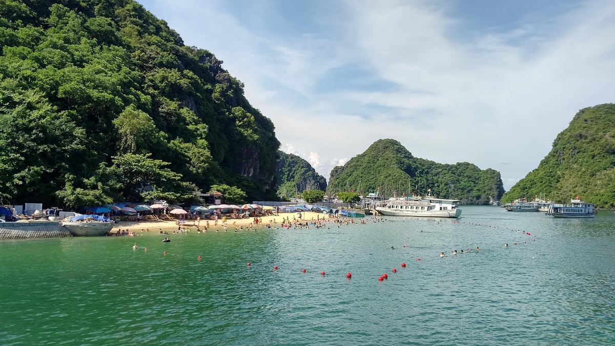 Bãi tắm nước xanh ngọc giữa các đảo đá vôi ở Vịnh Hạ Long, Quảng Ninh, mùa hè đông khách tắm biển