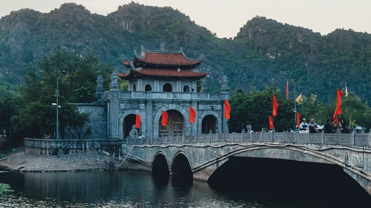 Cổng đá cổ và cầu vòm bắc qua hồ nước ở khu di tích cố đô Hoa Lư, Ninh Bình lúc chiều tà