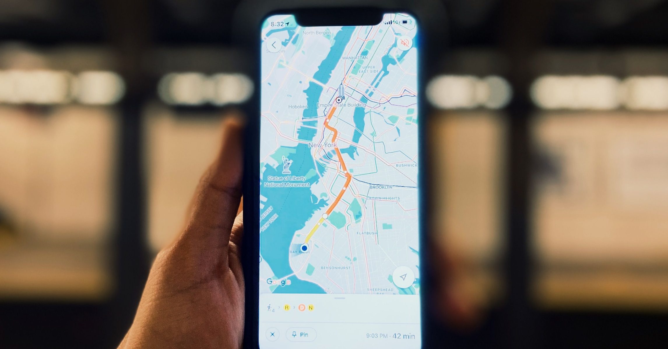 Người cầm điện thoại xem bản đồ có ghim địa danh Empire State Building và Statue of Liberty để tìm đường