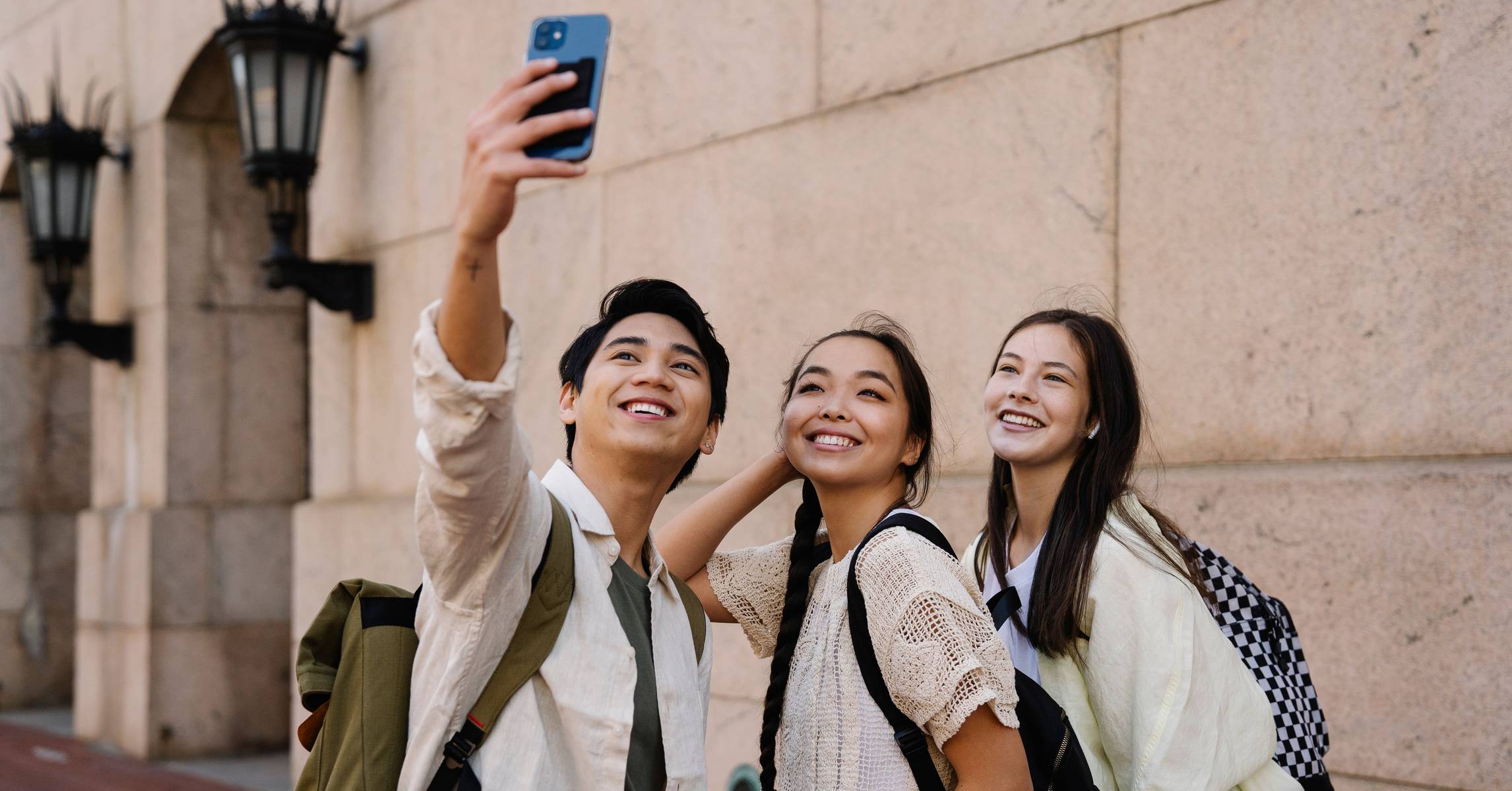 Ba người bạn đeo balo chụp ảnh nhóm khi đi chơi